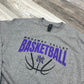 Gray t-shirt with 'Nodaway Valley Basketball' text and logo on a wooden surface